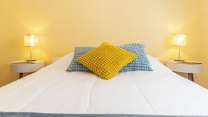 A bed with white bedding, two nightstands with lamps, and patterned pillows.
