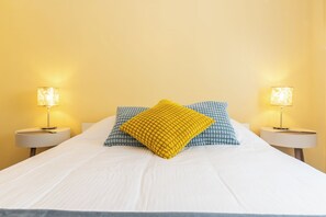 A bed with white bedding, two nightstands with lamps, and patterned pillows.