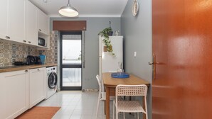 A compact kitchen with a washing machine, microwave, and a dining area with a table and chairs.