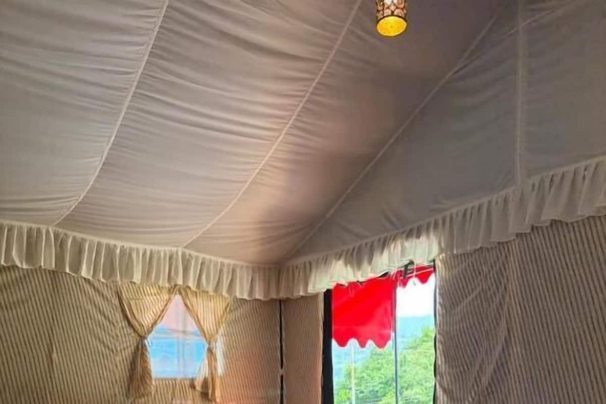 Una habitación tipo tienda de campaña con una cama, una silla y una mesa.