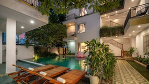 A modern building with a swimming pool, lounge chairs, and a staircase.