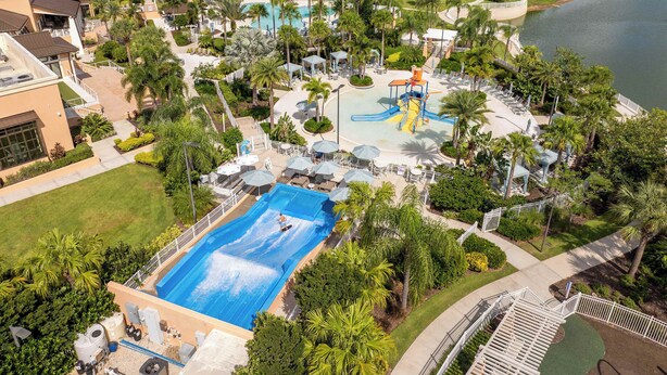 A residential area with a large swimming pool, palm trees, and a water park. - Stunning 4Bd w Pool Gameroom Solara Resort 9008 (Kissimmee)