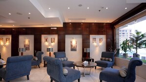 Un vestíbul d'hotel modern amb una zona de seients que inclou butaques blaves i una taula de cafè rodona.