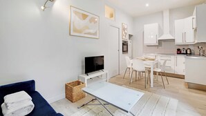 Un salon moderne avec un canapé, un téléviseur et un coin repas comprenant des chaises et une table.