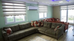 Una sala de estar con un sofá modular, un tapete estampado y una lámpara de techo.