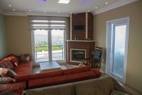 Una sala de estar con un sofá rojo, una chimenea y vistas al exterior.