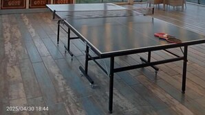 Una mesa de ping pong en una habitación amplia con vistas a montañas al atardecer.