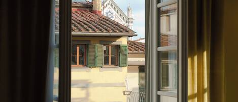 A view through a window of a building with a tiled roof, green shutters, and a star-shaped window.