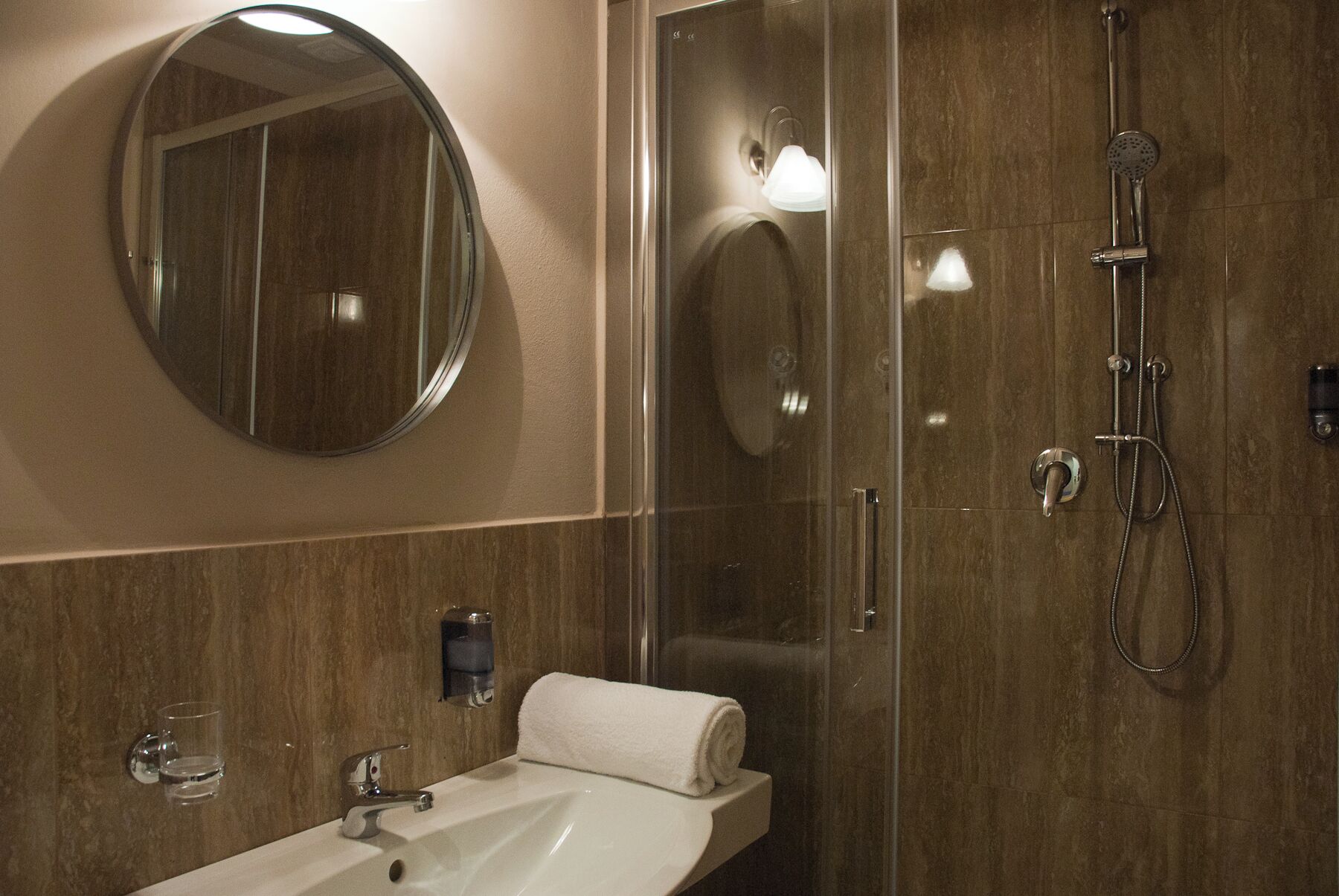 A bathroom with a sink, mirror, towel, and shower.