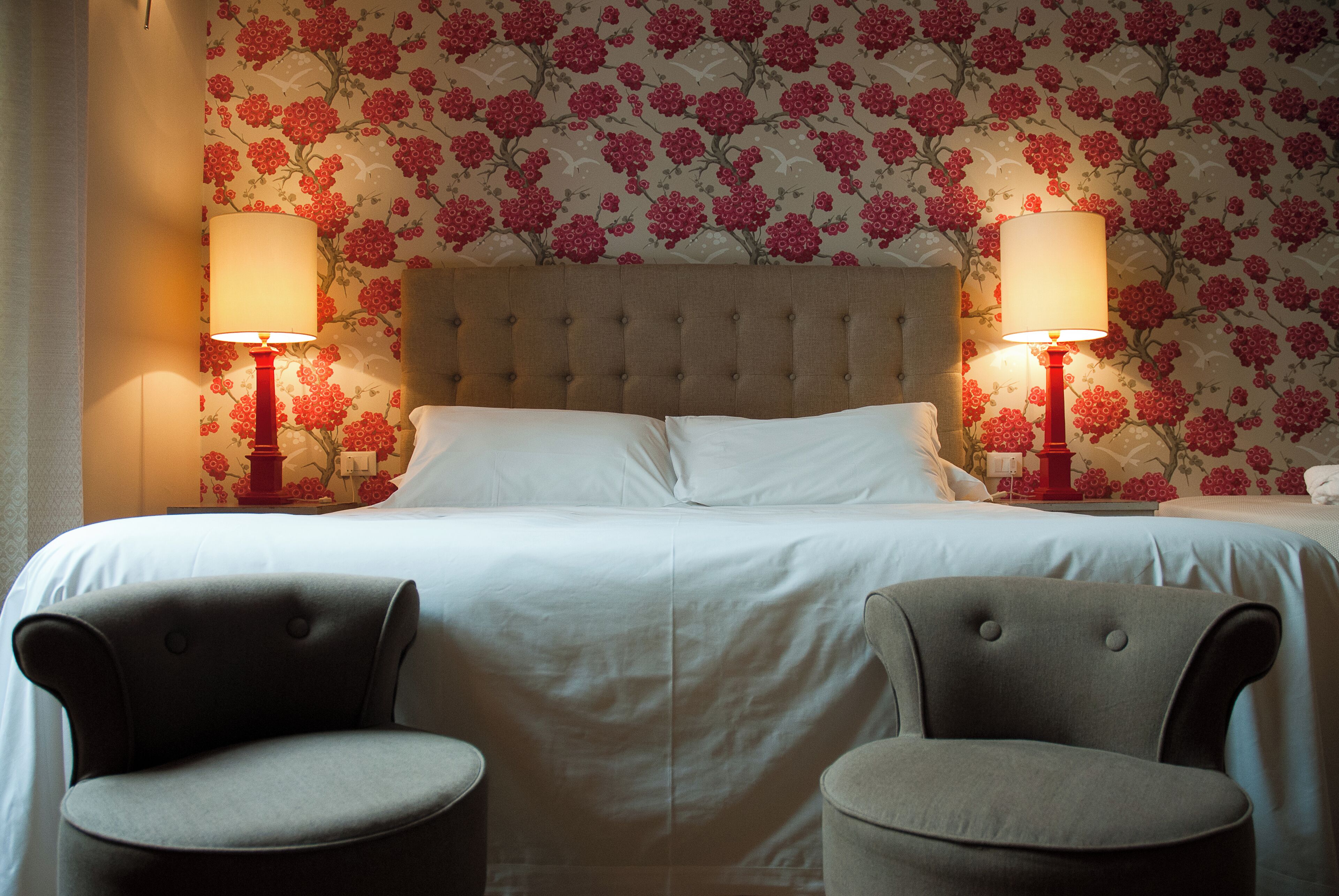 Una habitación de hotel con una cama grande, dos lámparas de noche y dos sillones.