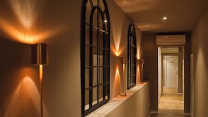 Un pasillo con ventanas arqueadas, iluminación empotrada y una puerta al final.