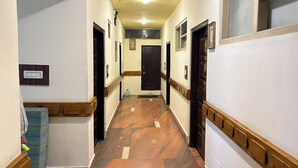 Un couloir étroit doté d’un plancher en bois, de murs blancs et de portes en bois foncé.