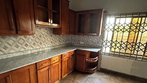 A kitchen with wooden cabinets, a tiled backsplash, and a window with a metal grid.