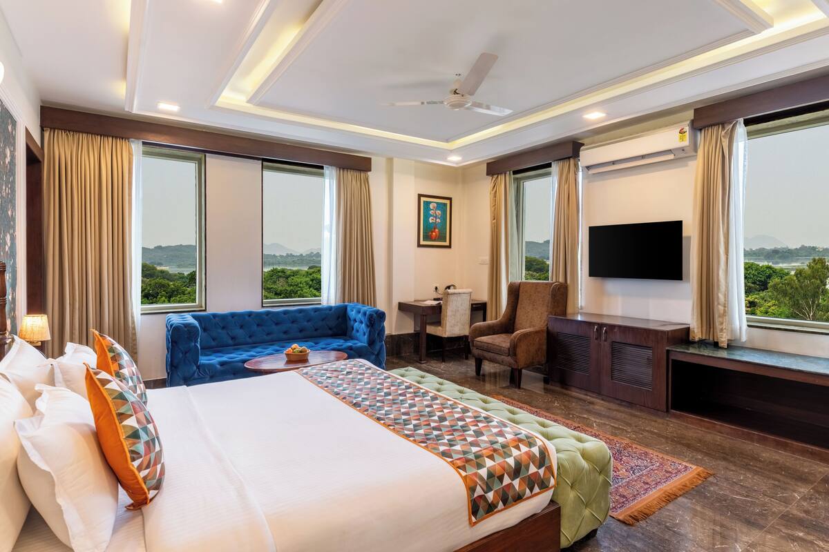 Ein Hotelzimmer mit einem großen Bett, einem blauen Sofa, einem Schreibtisch, einem Stuhl und einem Fernseher.