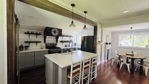 Una cocina amplia con una isla central, vigas de madera e iluminación colgante.