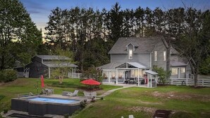 Una casa grande con piscina, mobiliario de exterior y patio cercado.