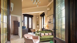 A living room with a green sofa, a pink armchair, and a dining area with chairs and a table. - Tuscan Refined Retreat (Firenze)