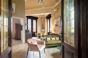 A living room with a green sofa, a pink armchair, and a dining area with chairs and a table. - Tuscan Refined Retreat (Firenze)
