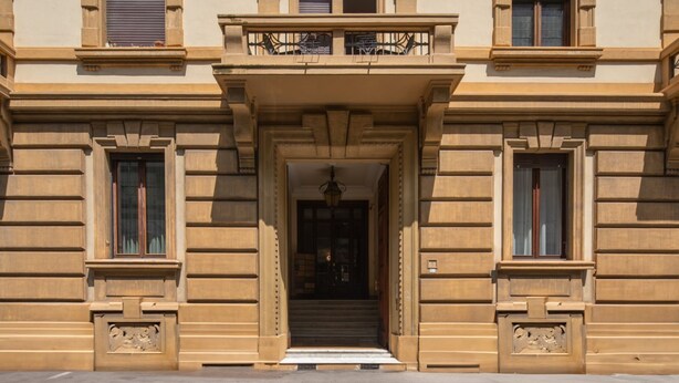 Un bâtiment doté d’une entrée imposante, de grandes fenêtres et d’un balcon orné de balustrades en fer forgé.