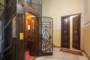 A hotel entrance with a metal spiral staircase, a decorative gate, and a set of double doors. - Tuscan Refined Retreat (Firenze)