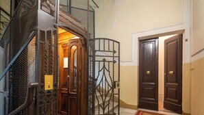 L’entrée d’un hôtel, avec un escalier en colimaçon en métal, une grille décorative et un ensemble de portes doubles.