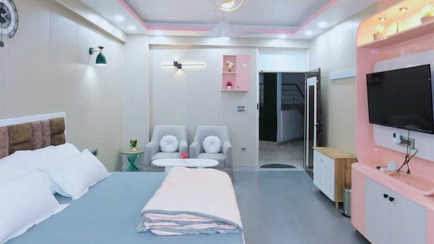 Une chambre d’hôtel moderne équipée d’un grand lit, d’un bureau, d’une chaise, d’une télévision et d’un ventilateur de plafond.