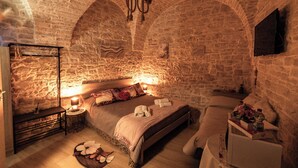 A stone-walled bedroom with a bed, bedside tables, and a small dresser.
