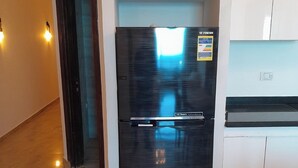 Una cocina moderna con un refrigerador negro, armarios blancos y piso de madera.