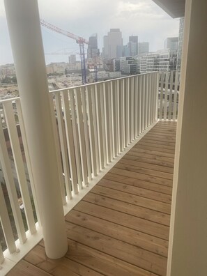 A wooden deck with white railings overlooking a cityscape with modern buildings and construction cranes. - New apartment with parking. La Défense near RER and Paris. Rooftop (Nanterre)