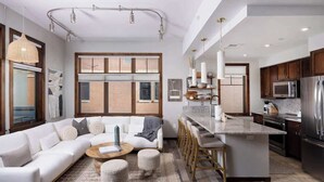 Une cuisine moderne dotée d’un grand îlot central, d’appareils électroménagers en acier inoxydable et d’un coin repas avec des tabourets de bar.