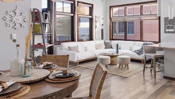 Un salon moderne avec un coin repas, comprenant une table à manger en bois, des chaises en osier et une grande fenêtre offrant une vue sur la ville.