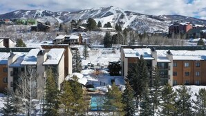 Un resort con varias edificaciones, piscina y una montaña nevada al fondo.