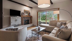 Una sala de estar con chimenea, sofá y televisión.