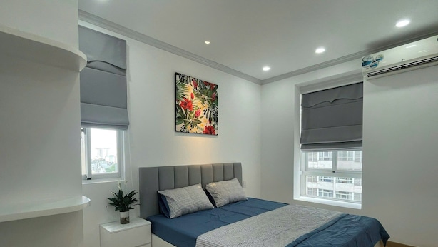 A modern bedroom with a bed, bedside table, and a window. - Nam Son Luxstay SG (Ho Chi Minh City)