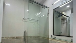 A modern bathroom with a glass-enclosed shower, a white sink, and a large mirror above the sink. - Nam Son Luxstay SG (Ho Chi Minh City)