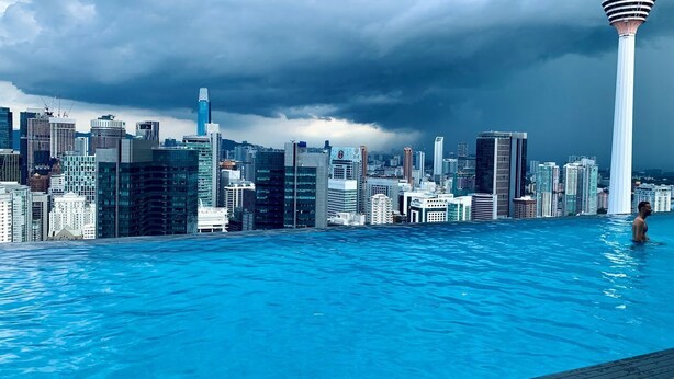 Une vue sur les toits d’une ville, avec une tour moderne et une grande piscine.