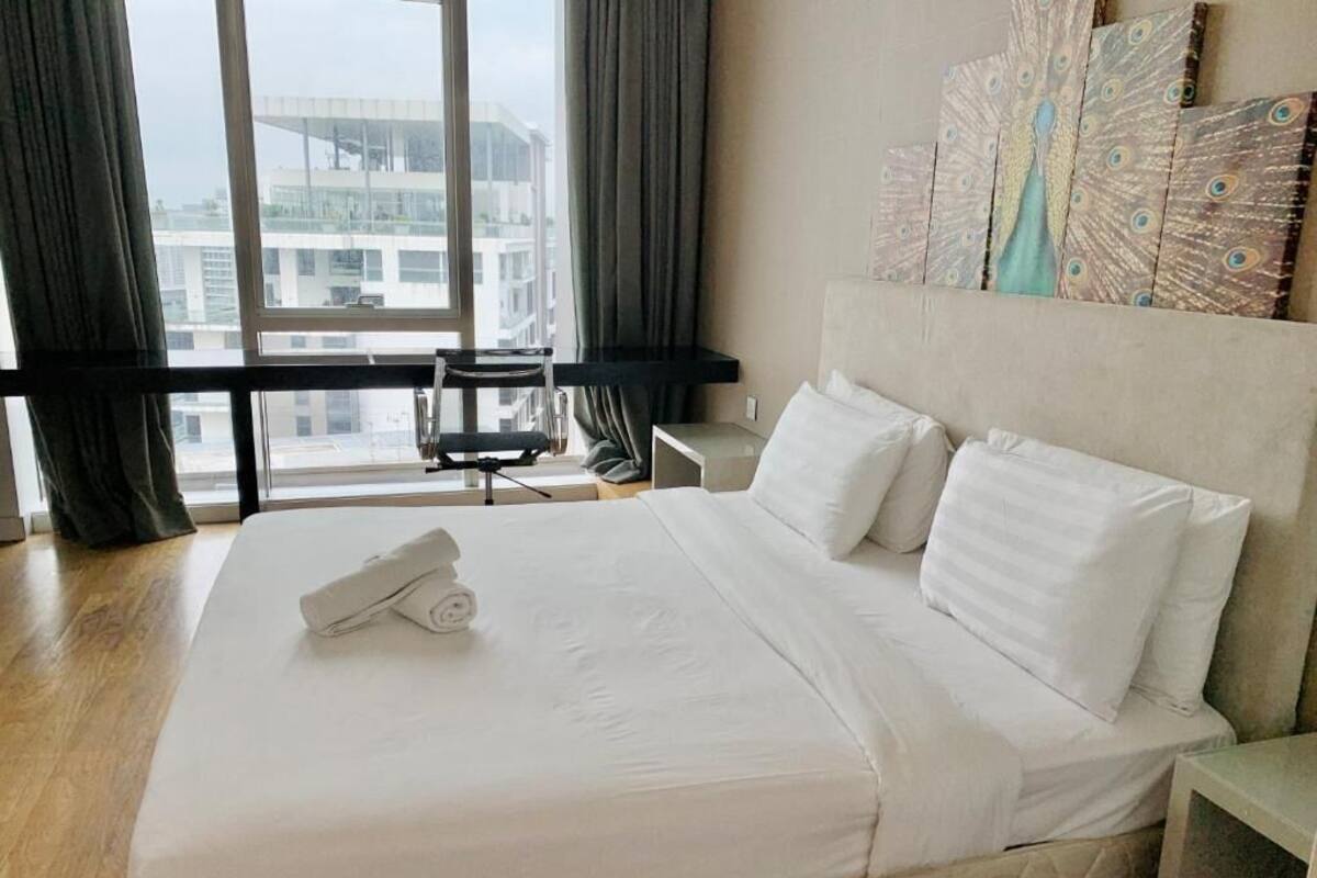 Une chambre d’hôtel avec un grand lit, un bureau et une vue sur la ville par la fenêtre.