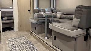 Un intérieur de camping-car compact comprenant un coin cuisine, un espace salon et une petite table à manger.