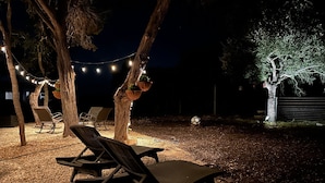 Un espace extérieur aménagé avec des fauteuils confortables et des guirlandes lumineuses.