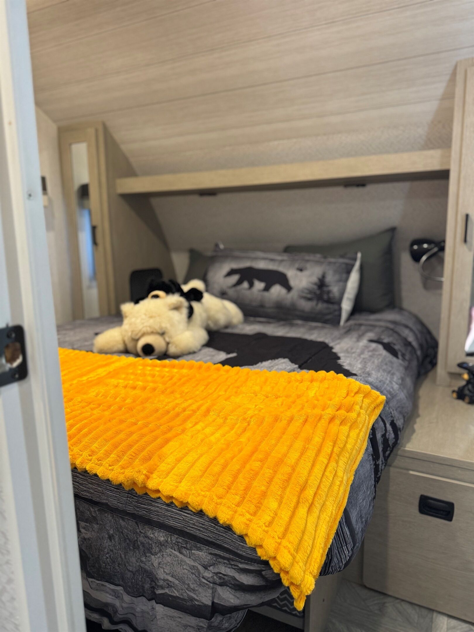 A bedroom with a bed, a teddy bear, a blanket, and a pillow with a bear design.