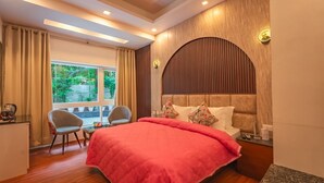 Habitación de hotel con una cama grande, dos sillas, un escritorio y vistas a zonas verdes.