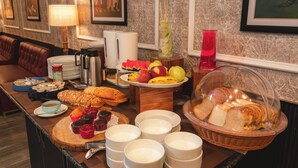 Un bufé de desayuno con diferentes alimentos, una estación de café y un área de estar con un sofá.