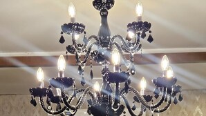 Un candelabro con múltiples luces y un cartel que dice "THE RAMPOUR" en una pared con textura.