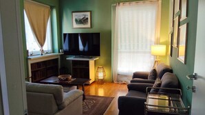 A living room with a sofa, a television, a lamp, and a window with curtains. - The Peak - Mountain view Aosta - Private parking! (Aosta)