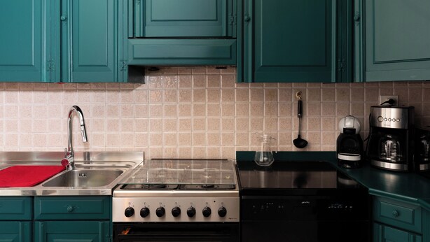 A kitchen with teal cabinets, a stainless steel sink, a gas stove, a dishwasher, and a coffee maker. - The Peak - Mountain view Aosta - Private parking! (Aosta)