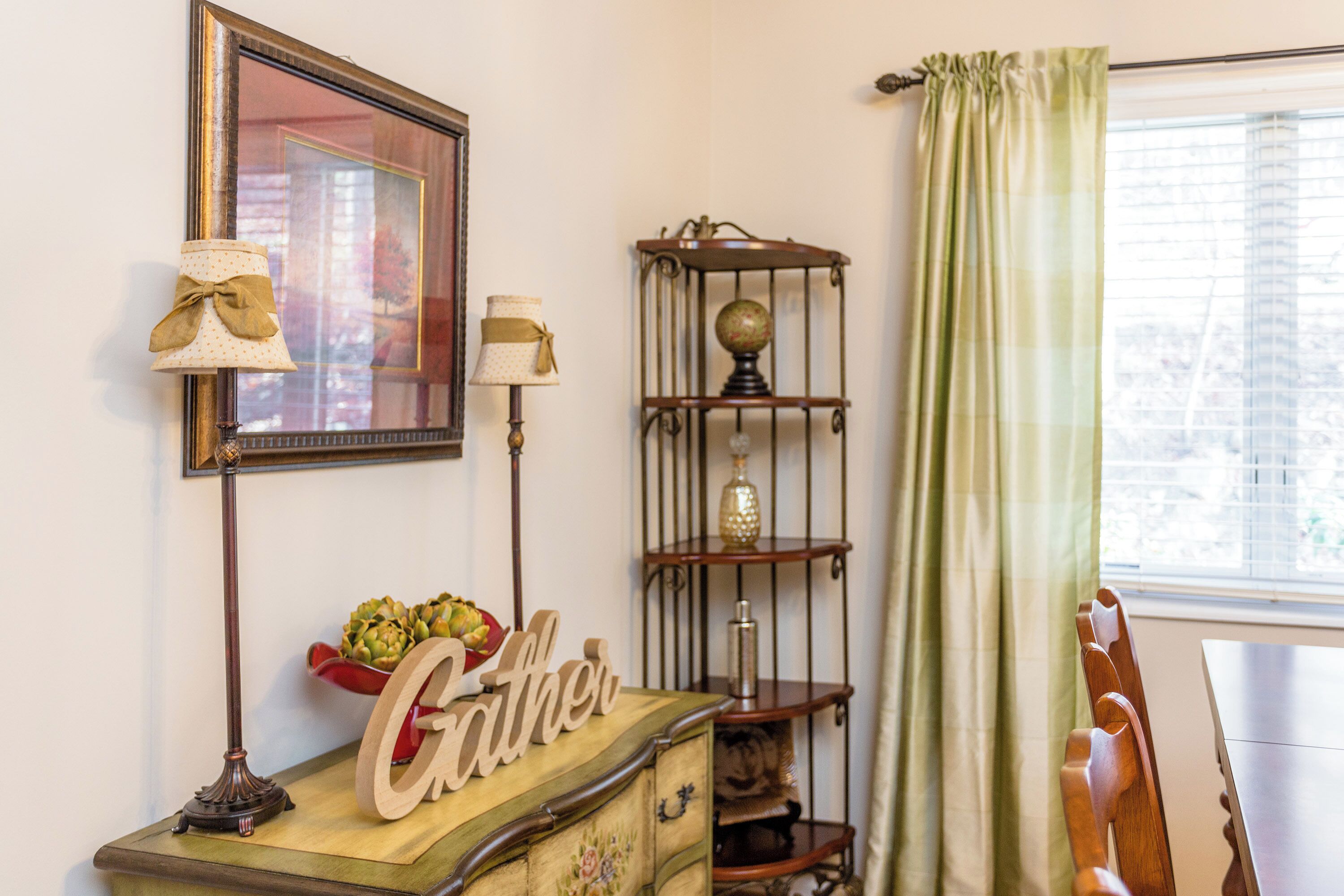 Une pièce au décor rétro, avec une commode en bois, un globe terrestre posé sur une étagère et une fenêtre agrémentée de rideaux.