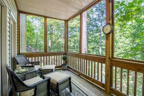 A covered porch with wicker furniture and a clock.