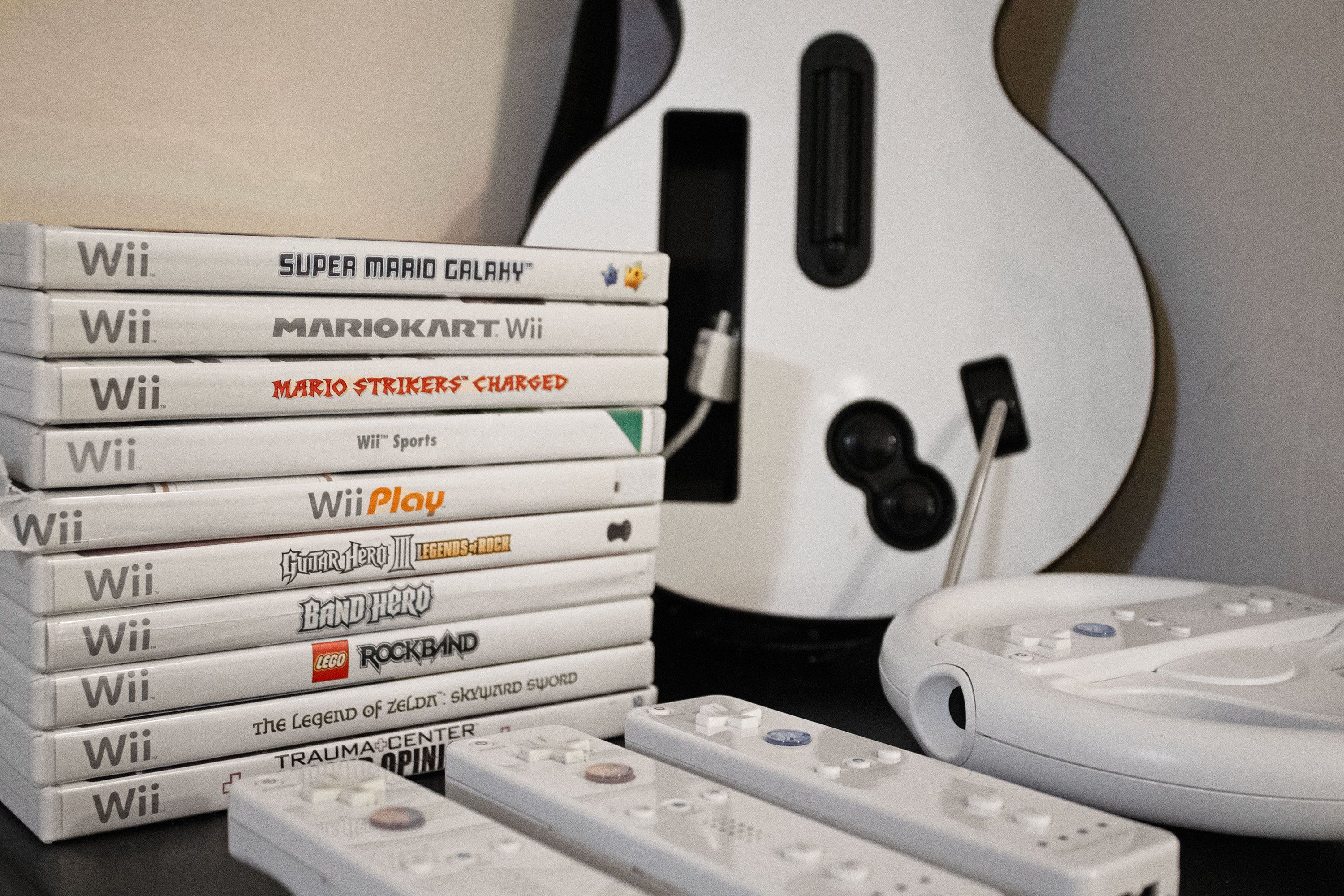 Pöydällä on pino Wii-pelien koteloita, kitara ja Wii-ohjaimia.