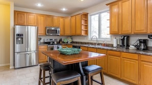 A kitchen with wooden cabinets, stainless steel appliances, a granite countertop, and a window providing natural light.
