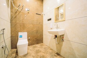 Et badeværelse med toilet, vask og brusebad.